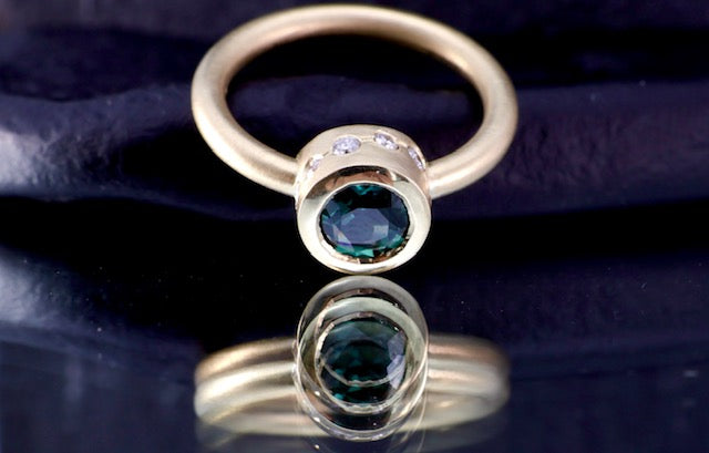 8. Robyn Clarke, Lagunas Ring 1, Laguna Verde, 18ct yellow gold, 1.10 carat round teal sapphire, 5 x 1.75mm EF/SI diamonds, 5 x 1.5mm EF/SI diamonds, size M