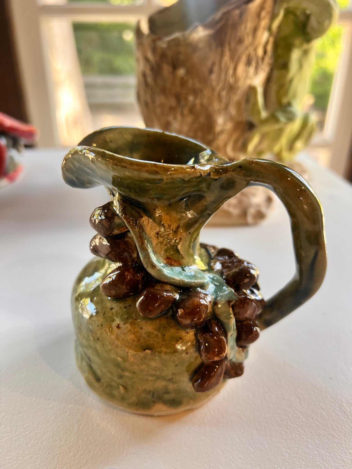 31. Sophia Di Luca, 2025, Monday 1A, "Heart of Sicily". An Olive oil jug with 3D shaped brown kalamata olives. Ceramic, Stoneware
