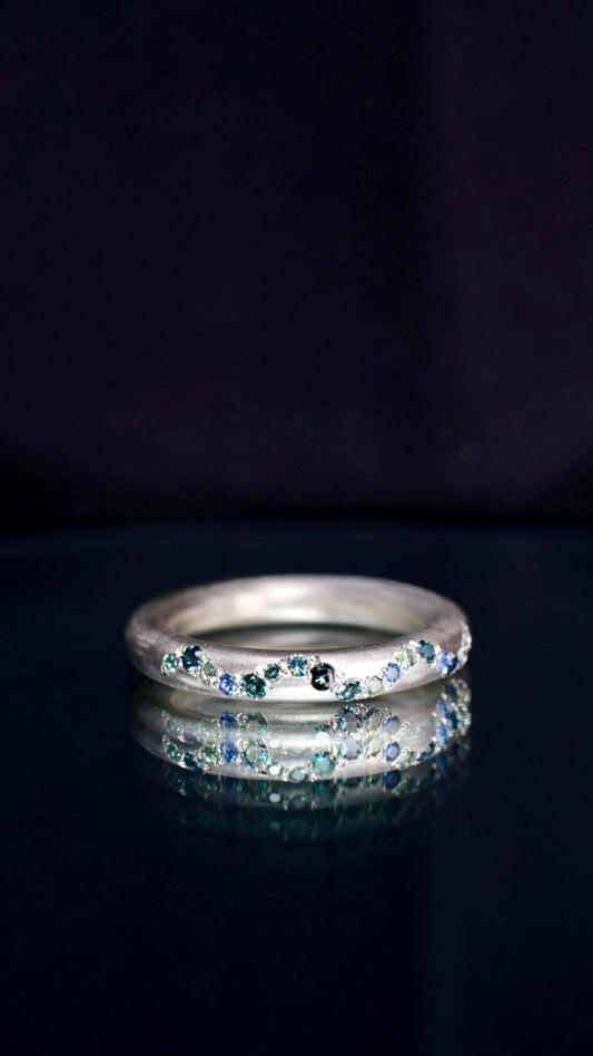 13. Robyn Clarke, Birrarung Ring 2, 3mm round 9ct white gold band with 17 x various teal, blue and green sapphires, size N