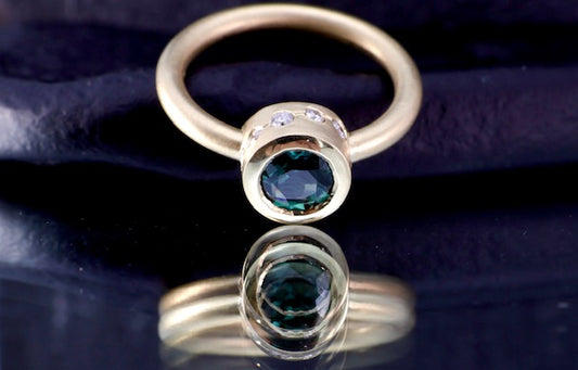 8. Robyn Clarke, Lagunas Ring 1,  Laguna Verde,  18ct yellow gold, 1.10 carat round teal sapphire, 5 x 1.75mm EF/SI diamonds, 5 x 1.5mm EF/SI diamonds, size M